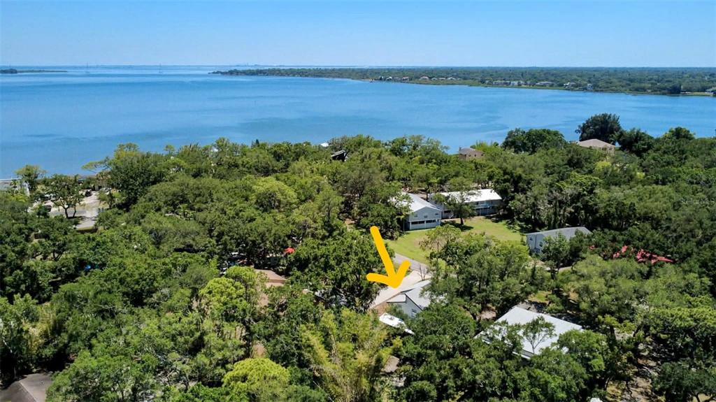 An aerial view shows a house surrounded by trees near a large body of water — 3071 HURON AVENUE, OLDSMAR, FL