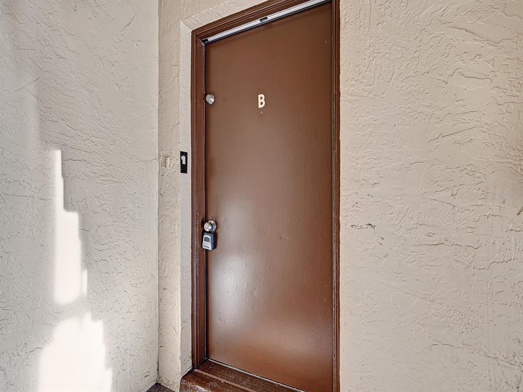 A brown exterior door labeled with the letter B is set into a textured wall — 625 N KEENE ROAD UNIT B, CLEARWATER, FL