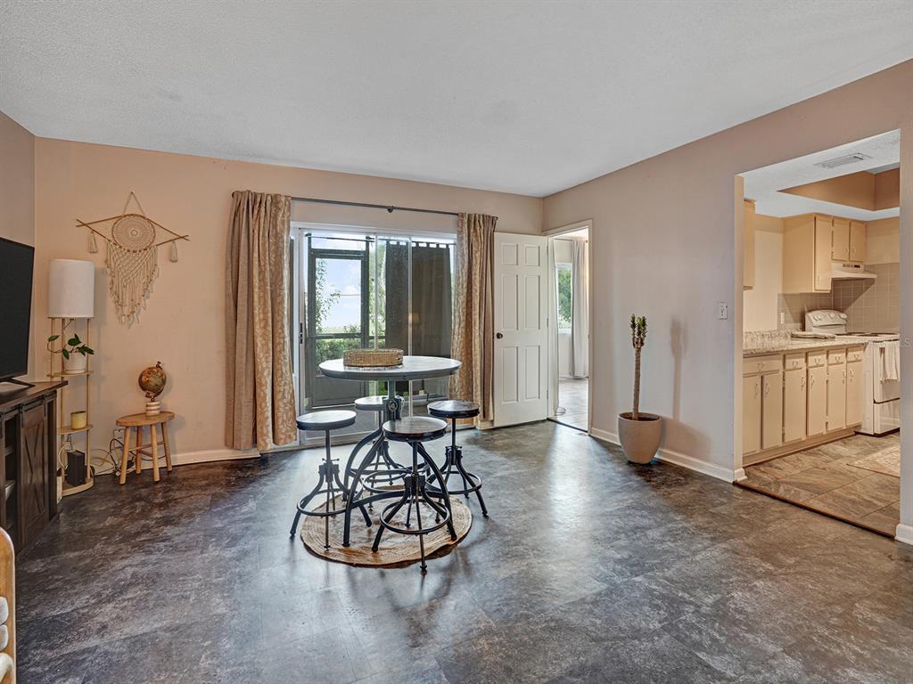 A dining area with a round industrial-style table and chairs sits on dark flooring — 625 N KEENE ROAD UNIT B, CLEARWATER, FL