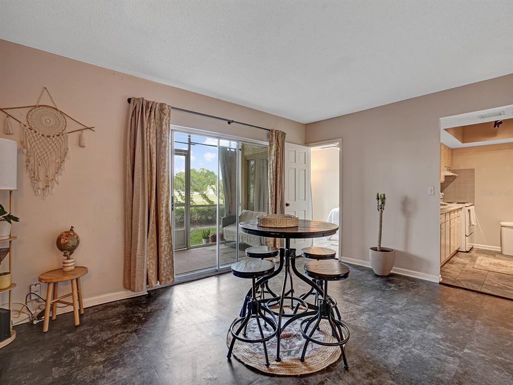 A dining area features a round metal table with stools, sliding glass doors, and tile flooring — 625 N KEENE ROAD UNIT B, CLEARWATER, FL