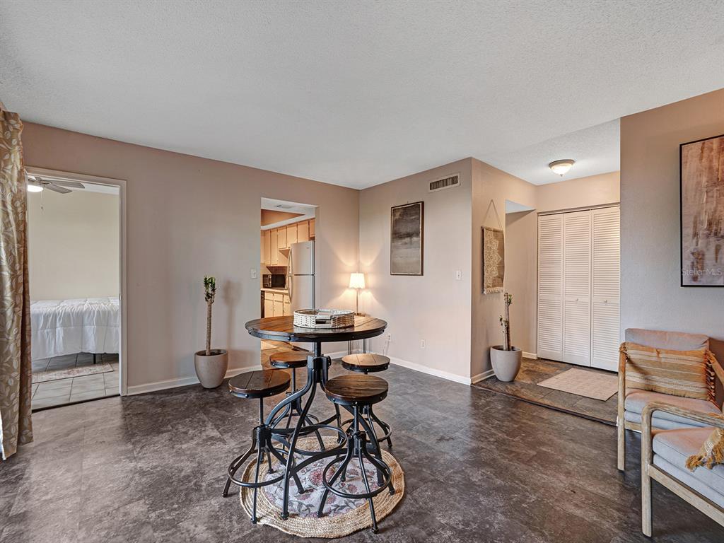 A dining area features a round industrial-style table with four stools on dark tile flooring — 625 N KEENE ROAD UNIT B, CLEARWATER, FL