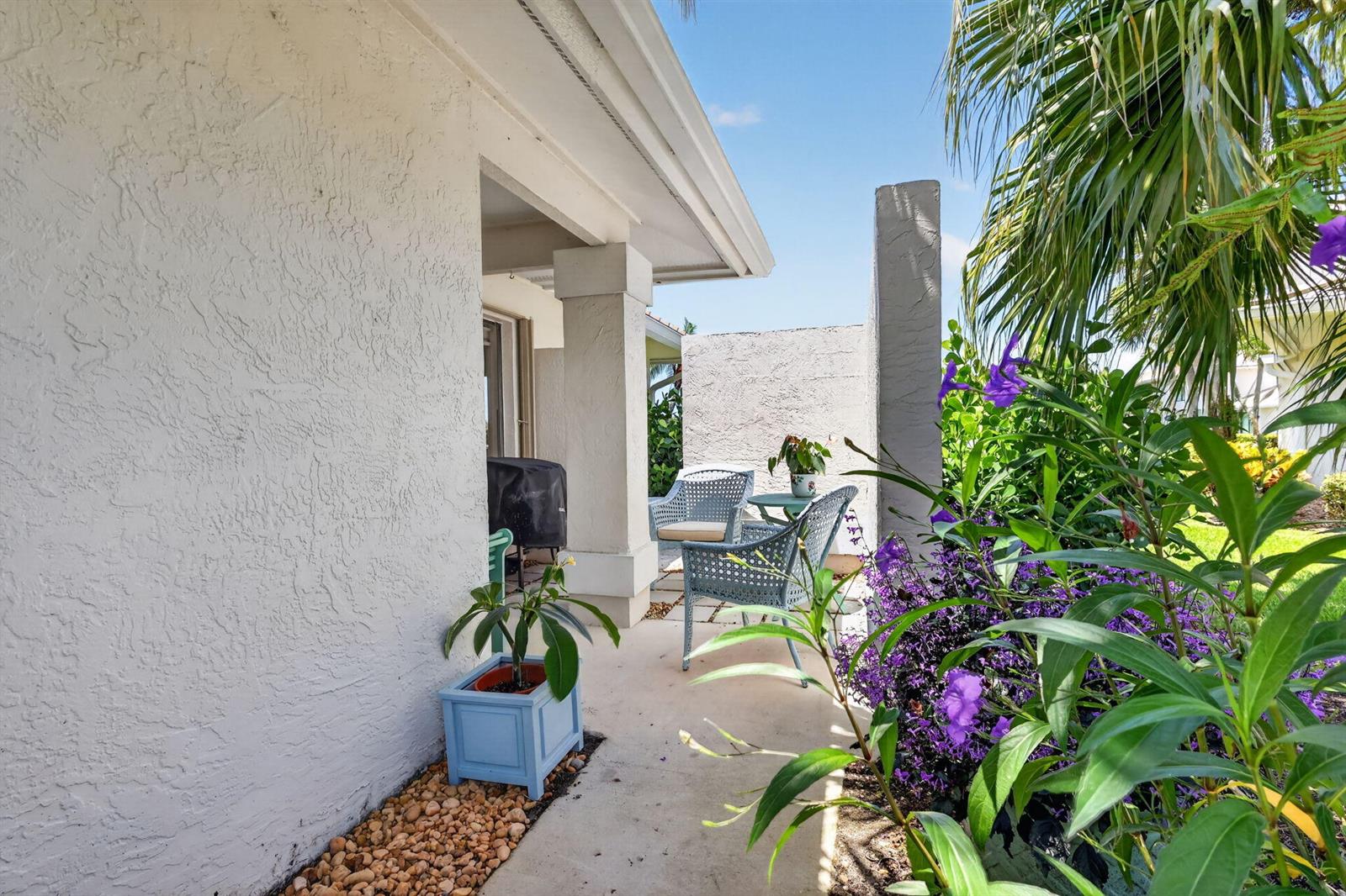 A kitchen features white cabinetry, a pink tiled backsplash, a marble island, and palm-patterned wallpaper — 5632 SE Foxcross Place, Stuart FL 34997, STUART, FL