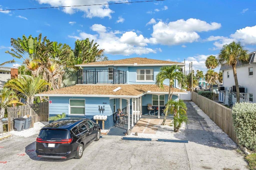 A two-story blue house with a shingled roof, a balcony, and a paved driveway — 644 72ND AVENUE, ST PETE BEACH, FL