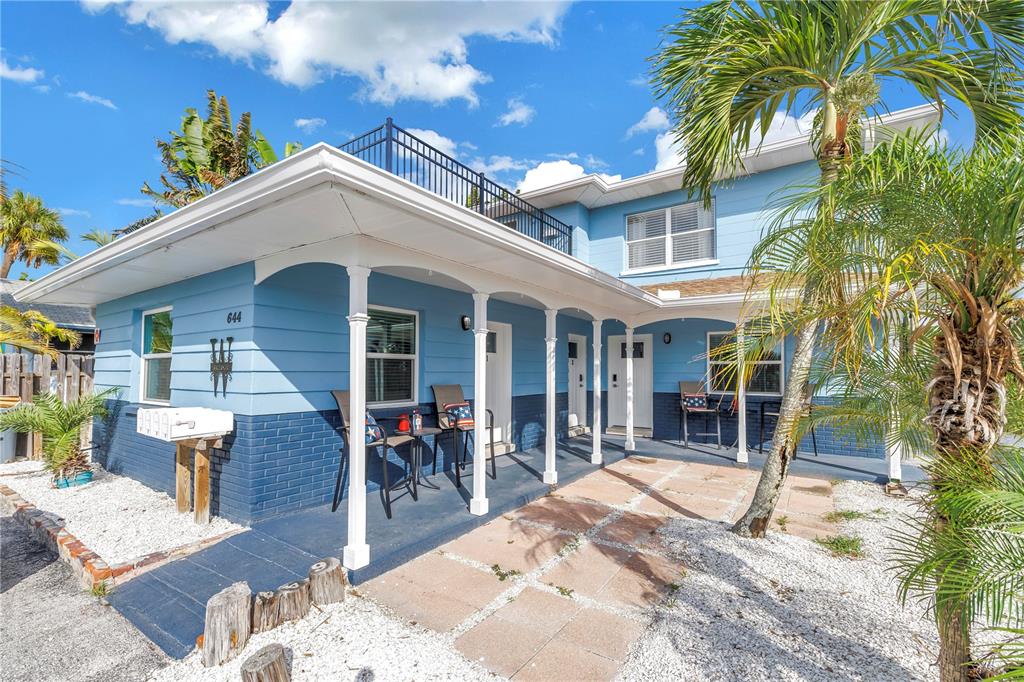 A two-story blue house features a covered porch, white columns, and a rooftop deck — 644 72ND AVENUE, ST PETE BEACH, FL
