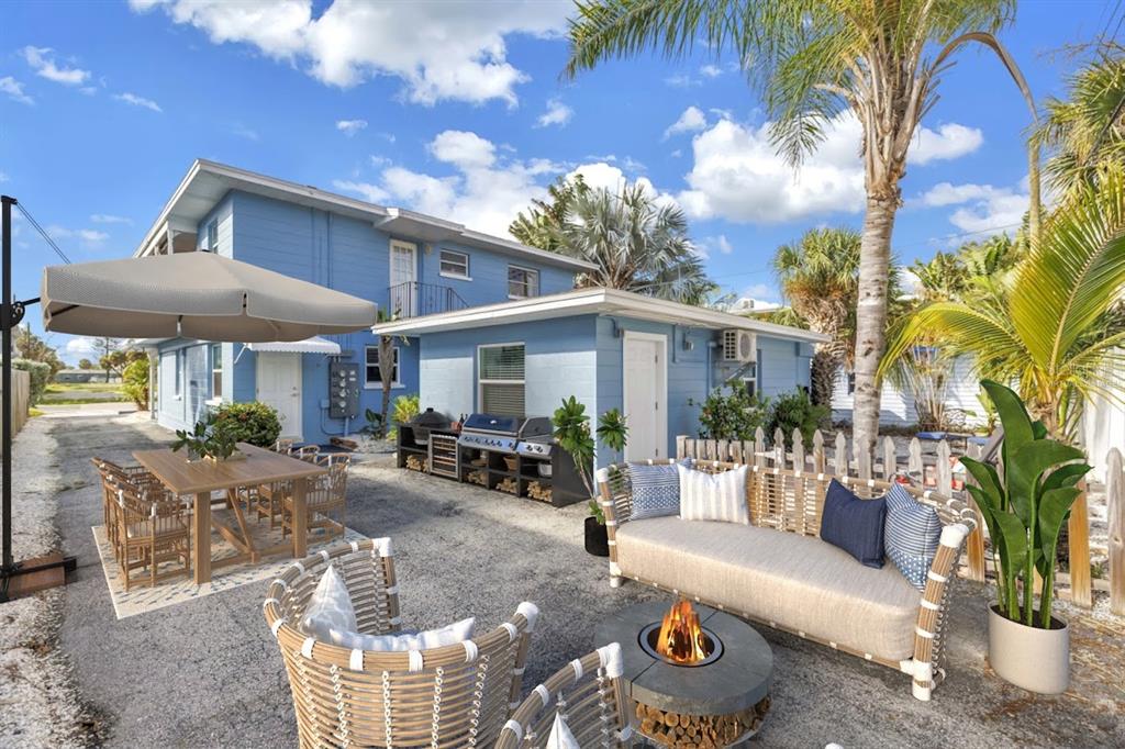 A blue two-story building features an outdoor patio with a dining set and fire pit — 644 72ND AVENUE, ST PETE BEACH, FL