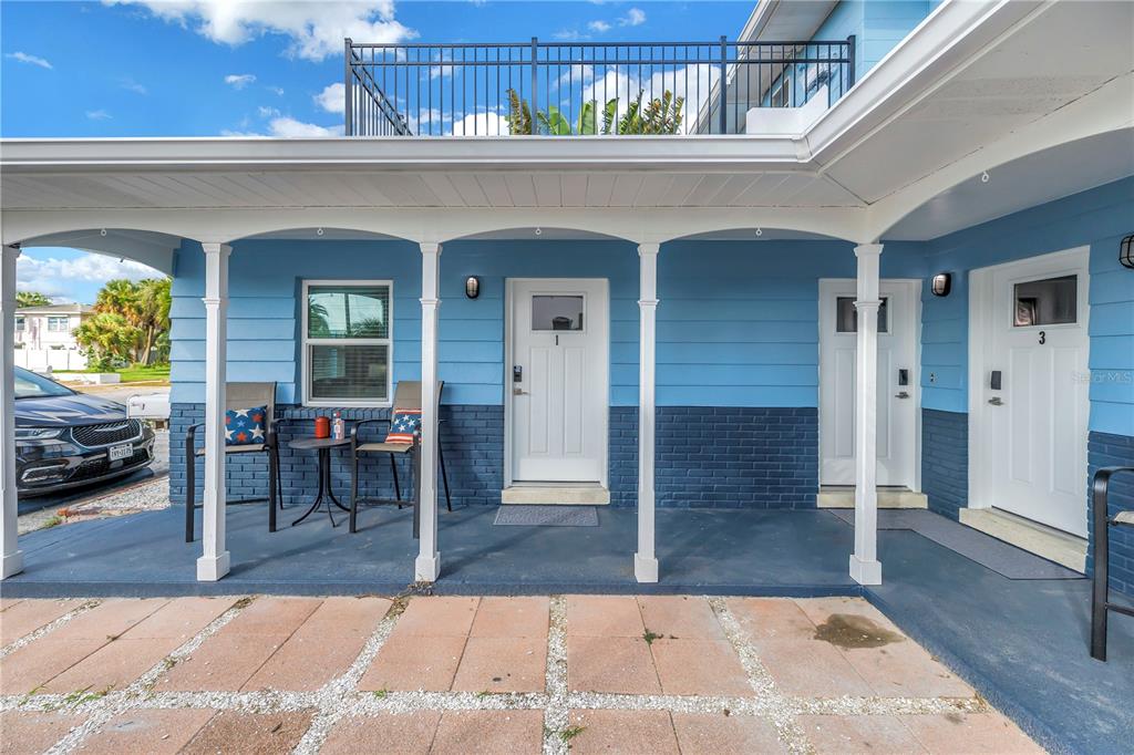 A blue exterior building with a covered porch, two white doors, and a rooftop balcony — 644 72ND AVENUE, ST PETE BEACH, FL