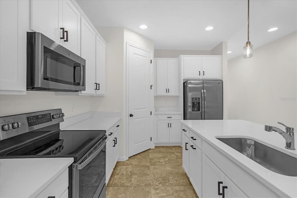 A kitchen features white cabinets, stainless steel appliances, a center island, and tile flooring — 551 LAKE SMART BOULEVARD, WINTER HAVEN, FL