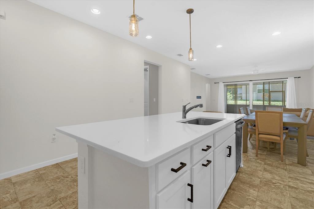 A kitchen island with a white countertop and sink sits in front of a dining area — 551 LAKE SMART BOULEVARD, WINTER HAVEN, FL