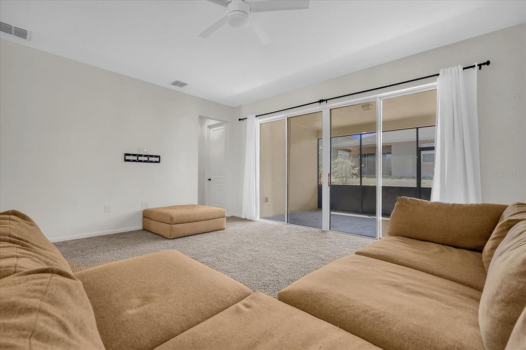 A living room features tan sectional seating, carpeted flooring, and sliding glass doors to a patio — 551 LAKE SMART BOULEVARD, WINTER HAVEN, FL