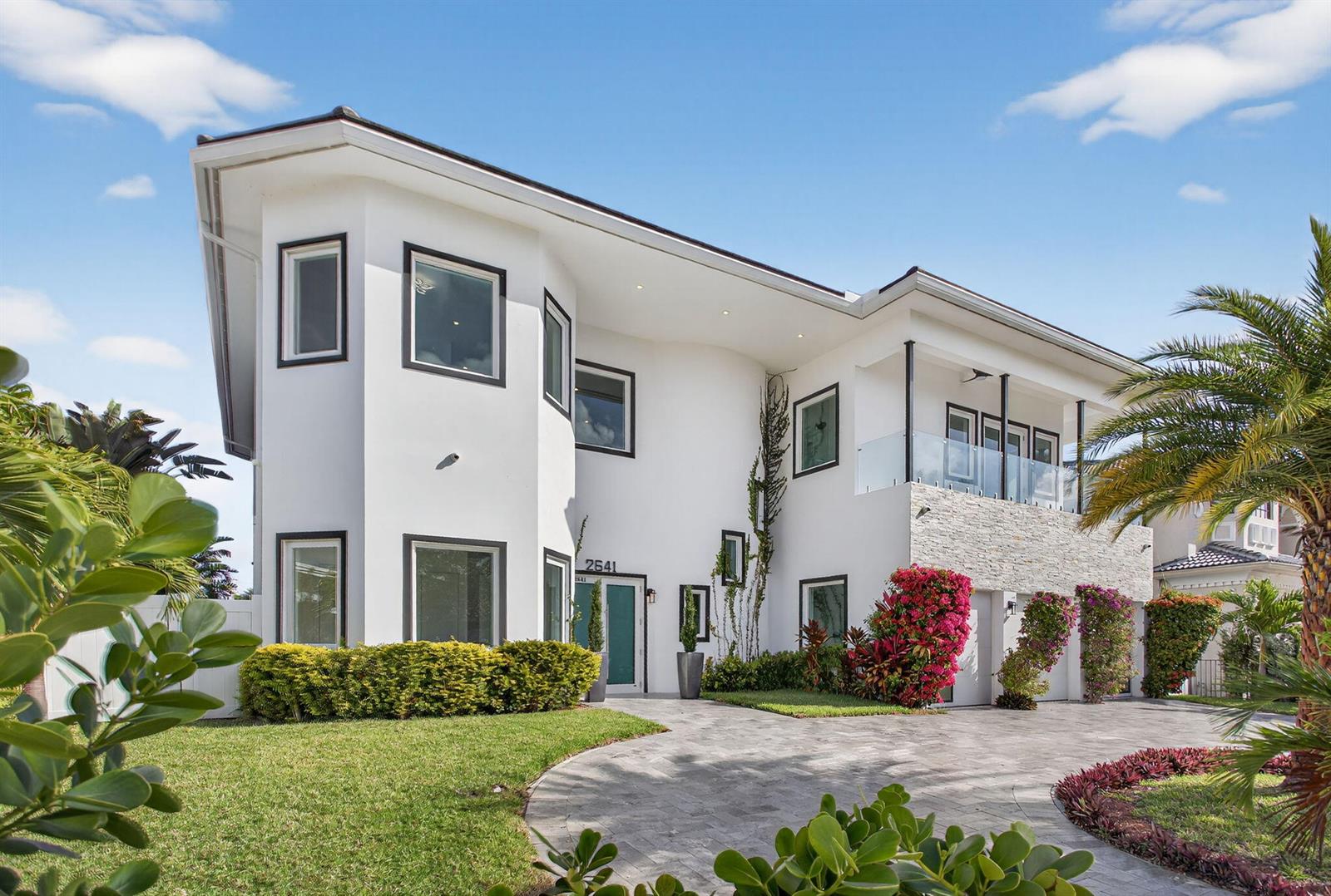 A modern two-story white house with a stone-accented balcony and a paved circular driveway — 2641 NE 48th Street, Lighthouse Point FL 33064, LIGHTHOUSE POINT, FL