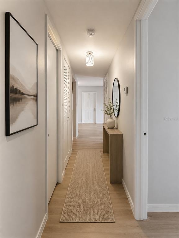 A hallway features light wood flooring, a runner rug, a console table, and wall art — 1223 S PINE RIDGE CIRCLE UNIT 23, SANFORD, FL