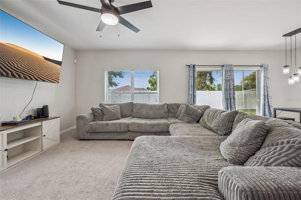 A living room features a large gray sectional sofa, carpeted floors, and a wall-mounted television — 240 WHISPERING PINES WAY, DAVENPORT, FL