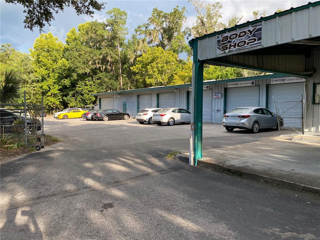 A commercial building with multiple garage bays and several parked cars in the lot — 2625 N MAIN STREET, GAINESVILLE, FL