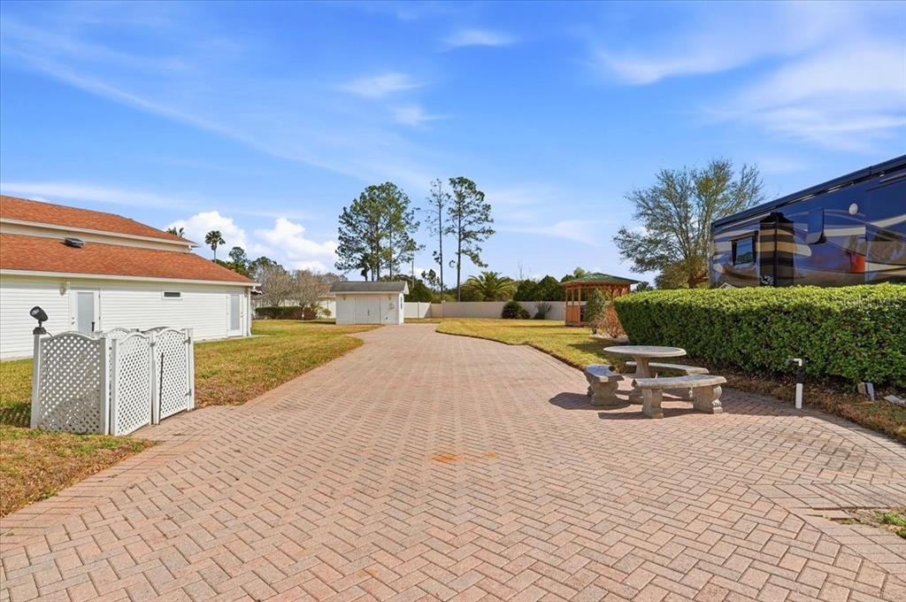 A paved driveway leads toward a small shed and gazebo in a grassy backyard — MOTORCOACH DRIVE S, POLK CITY, FL