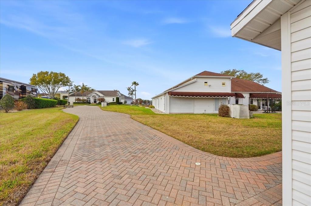 A paved driveway leads toward a white house with a brown roof and palm trees — MOTORCOACH DRIVE S, POLK CITY, FL