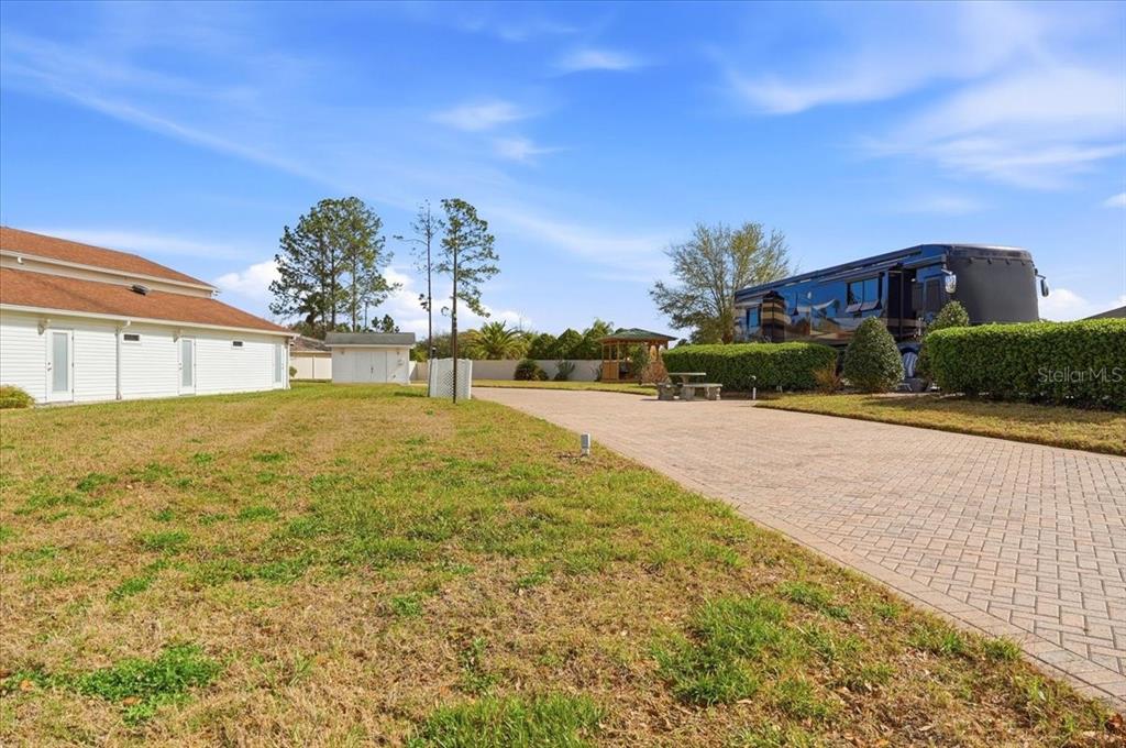 A paved driveway leads to a large RV parked next to a house and gazebo — MOTORCOACH DRIVE S, POLK CITY, FL