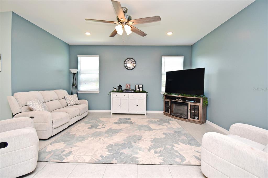 A living room features light blue walls, a floral area rug, and neutral-colored furniture — 33291 REMBRANDT LANE, SORRENTO, FL