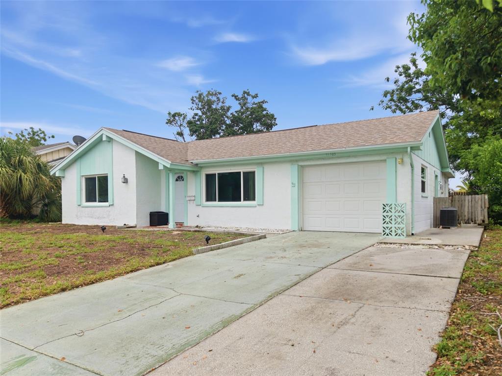 A single-story house with a white stucco exterior, mint green trim, and an attached garage — 12305 PARTRIDGE HILL ROW, HUDSON, FL