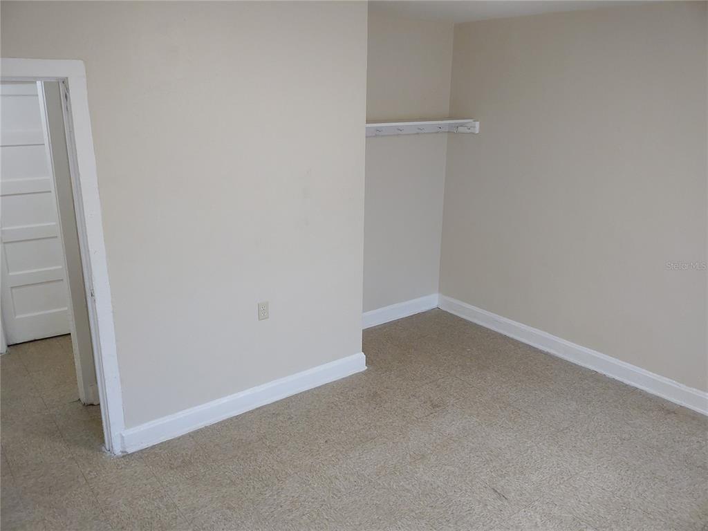 An empty room with beige walls, carpeted flooring, a doorway, and a small wall-mounted shelf — 1911 W 26TH STREET, JACKSONVILLE, FL