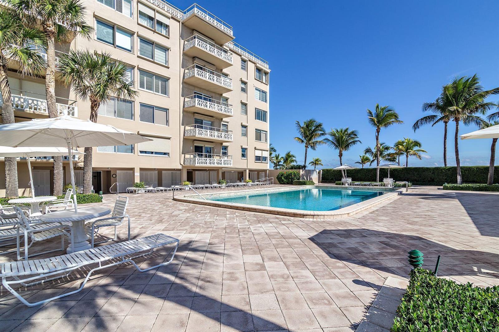 A multi-story apartment building overlooks a swimming pool and a paved patio with lounge chairs — 170 N Ocean Boulevard # 409, Palm Beach FL 33480, PALM BEACH, FL