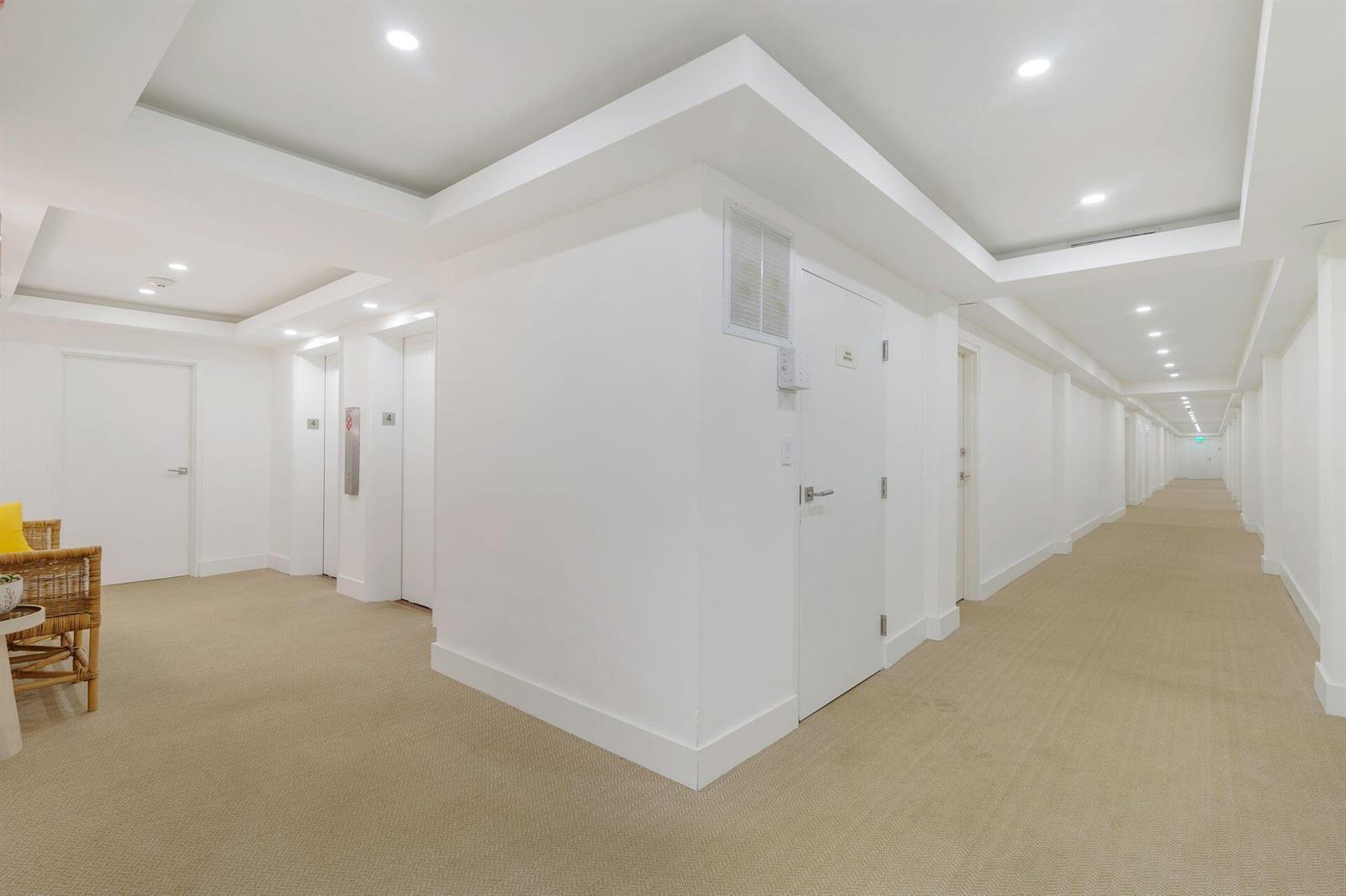 A bright, carpeted hallway features white walls, recessed lighting, and elevator doors on the left — 170 N Ocean Boulevard # 409, Palm Beach FL 33480, PALM BEACH, FL