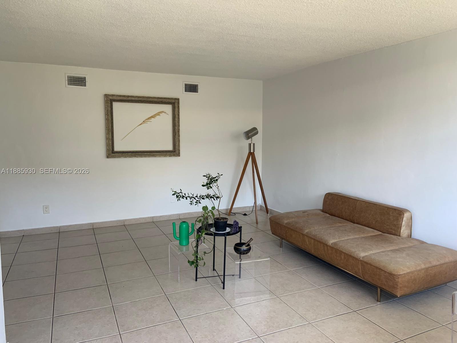 A living room features a brown leather sofa, a tripod floor lamp, and tile flooring — 360 Meridian Ave # 4C, Miami Beach FL 33139, MIAMI BEACH, FL