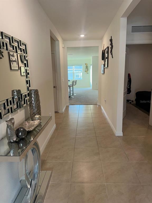 A tiled hallway leads from a mirrored console table toward an open living area — 2184 DOE RUN DRIVE, DAVENPORT, FL