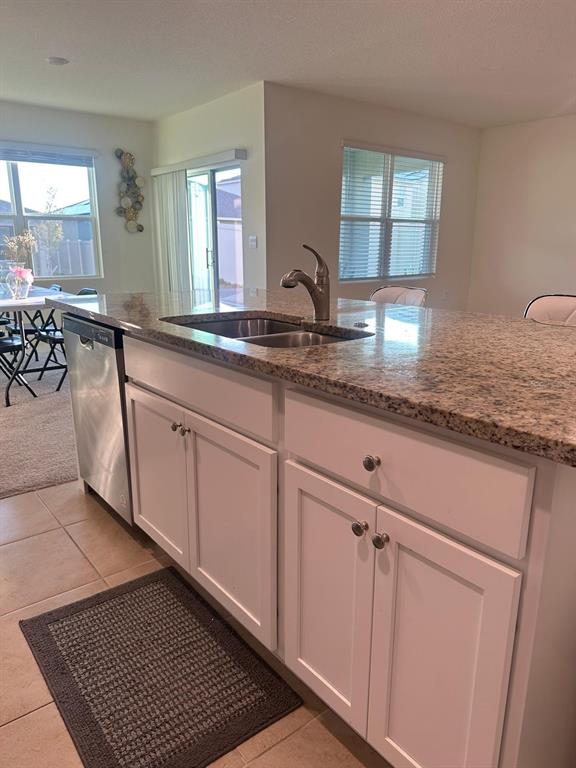 A kitchen island with a stainless steel sink, granite countertop, and white cabinets — 2184 DOE RUN DRIVE, DAVENPORT, FL