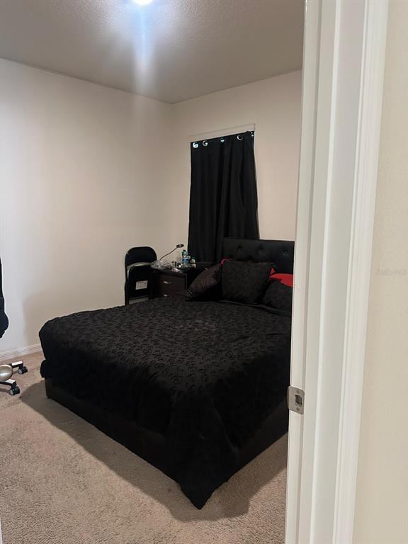 A bedroom features a black bed with matching bedding, a nightstand, and a window with curtains — 2184 DOE RUN DRIVE, DAVENPORT, FL