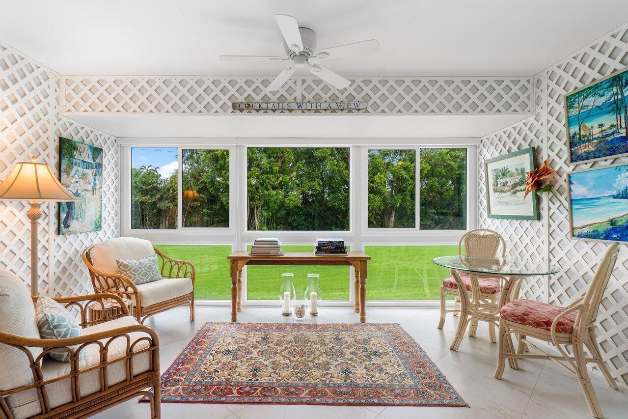 A sunroom features wicker furniture, a patterned area rug, and lattice walls overlooking greenery — 11312 Quail Covey Road, Boynton Beach FL 33436, BOYNTON BEACH, FL