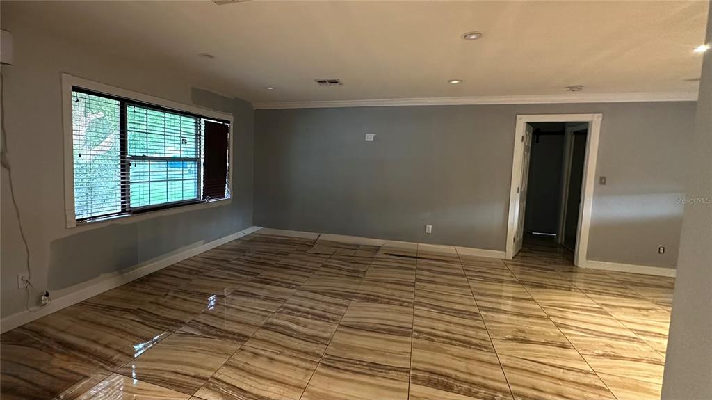 An empty room features gray walls, recessed lighting, and polished brown-and-white marble-patterned tile flooring — 5354 LANYARD COURT, WINTER PARK, FL