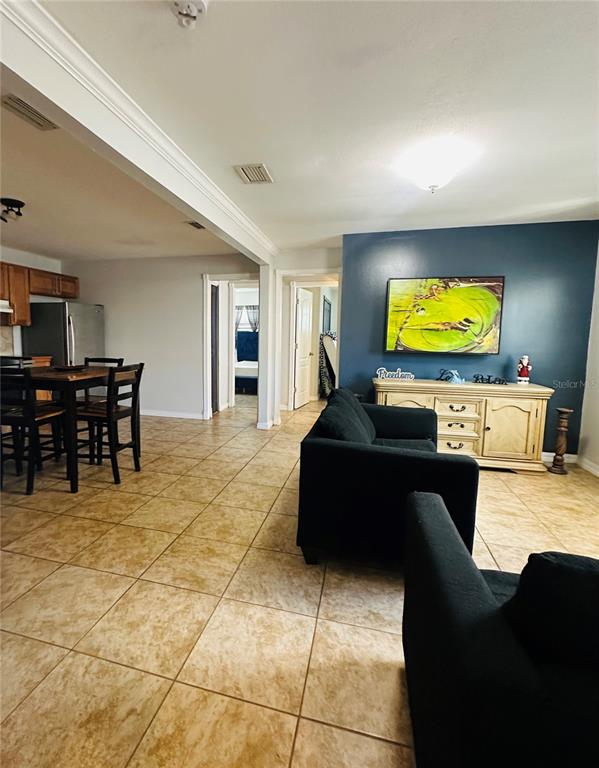 A living room with tile floors and a blue accent wall leads to a kitchen — 5354 LANYARD COURT, WINTER PARK, FL
