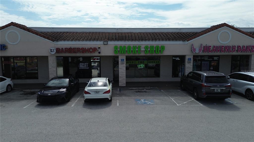 A strip mall exterior features a barbershop, a smoke shop, and a dance studio — 11601 S ORANGE BLOSSOM TRAIL UNIT 103, ORLANDO, FL