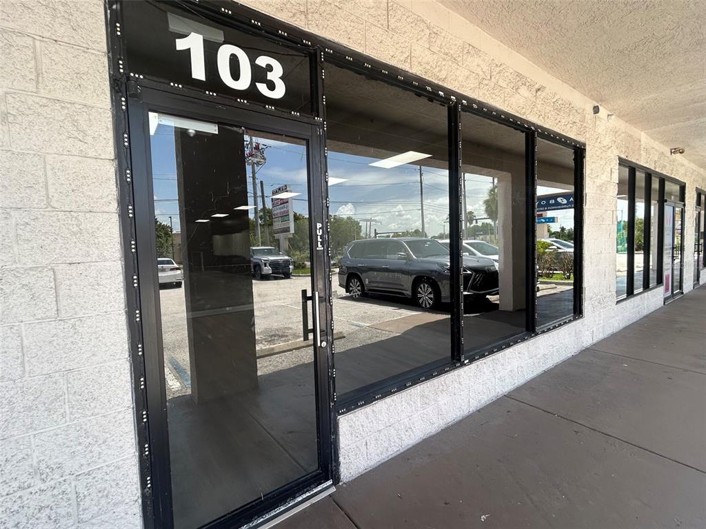 The exterior view shows a commercial storefront with a glass door labeled 103 — 11601 S ORANGE BLOSSOM TRAIL UNIT 103, ORLANDO, FL
