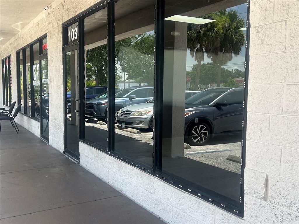 The exterior of a commercial building features a glass storefront with a numbered entrance door — 11601 S ORANGE BLOSSOM TRAIL UNIT 103, ORLANDO, FL