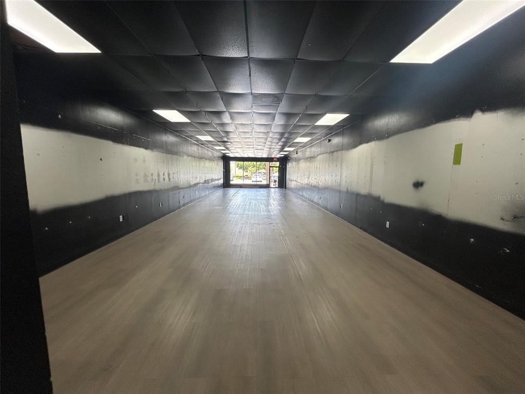 An empty commercial space features a black drop ceiling, light wood flooring, and unfinished walls — 11601 S ORANGE BLOSSOM TRAIL UNIT 103, ORLANDO, FL