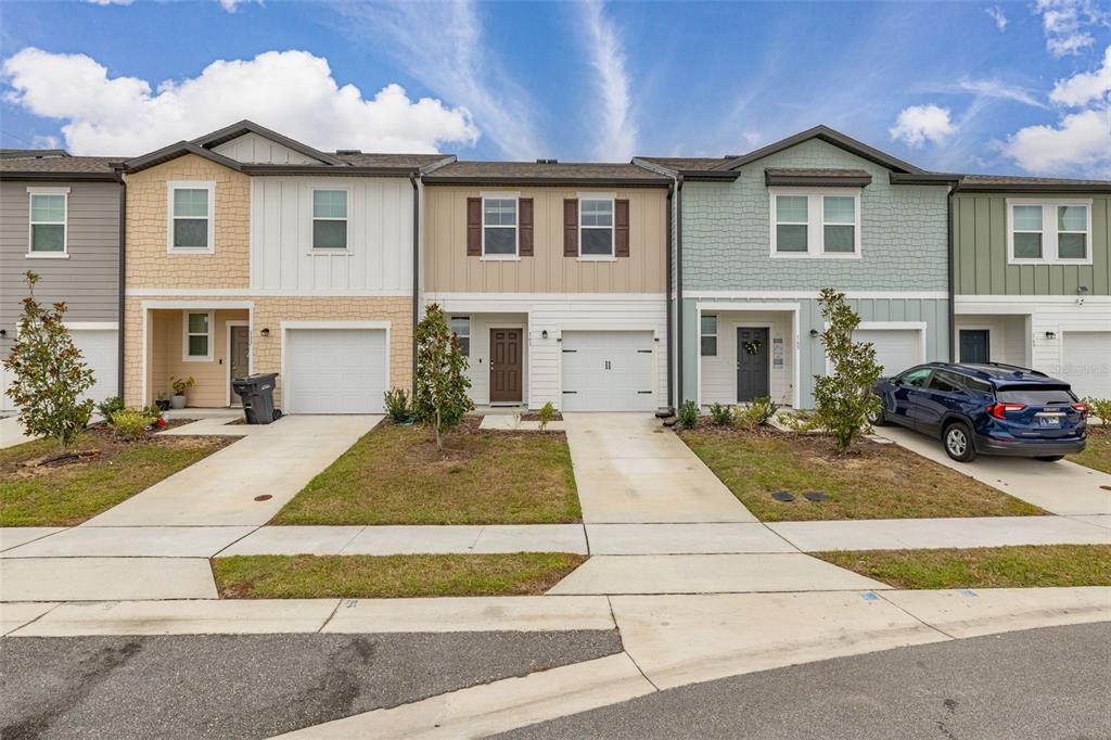 A row of three two-story townhomes with garages, driveways, and small front lawns — 161 MANDOVI STREET, DAVENPORT, FL
