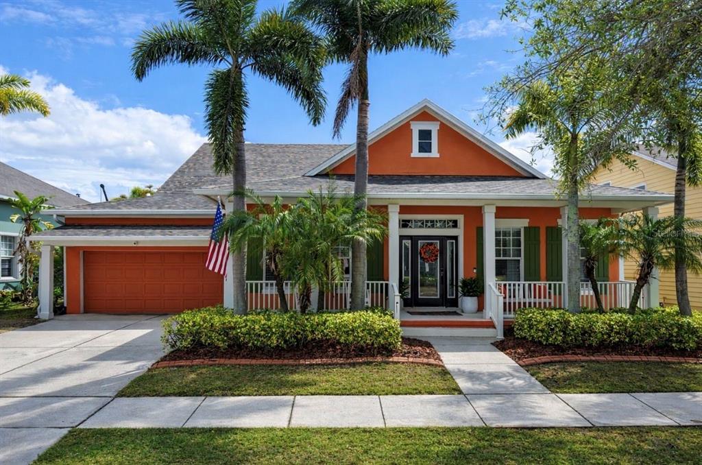 A single-story orange house with a front porch, garage, and palm trees in the yard — 5715 SEA TROUT PLACE, APOLLO BEACH, FL