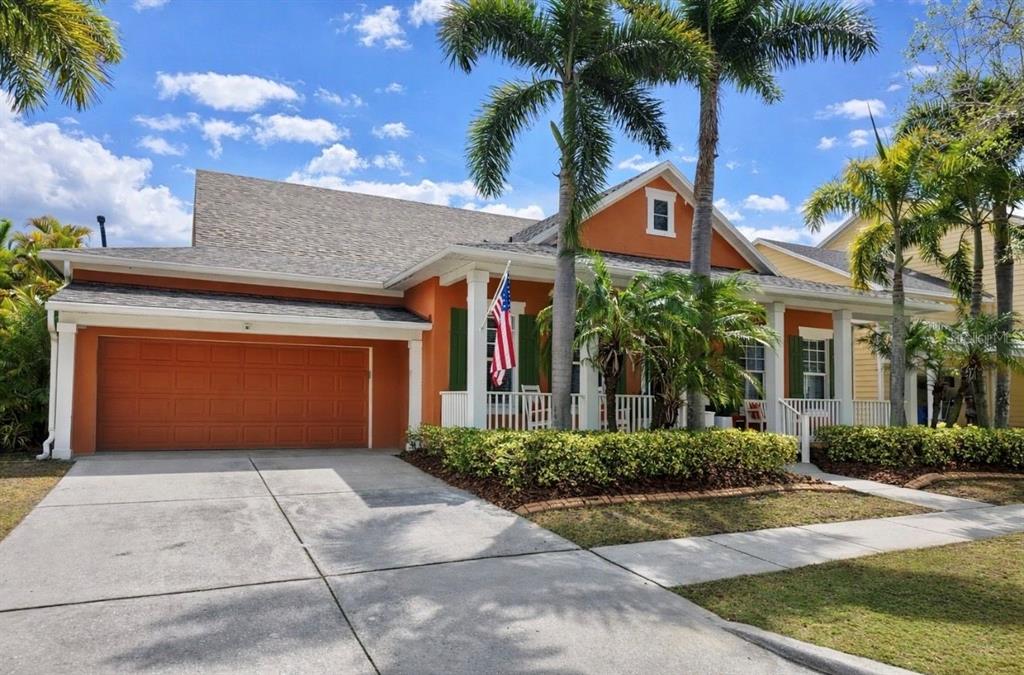 A single-story house with a front porch, palm trees, and exterior lighting at dusk — 5715 SEA TROUT PLACE, APOLLO BEACH, FL