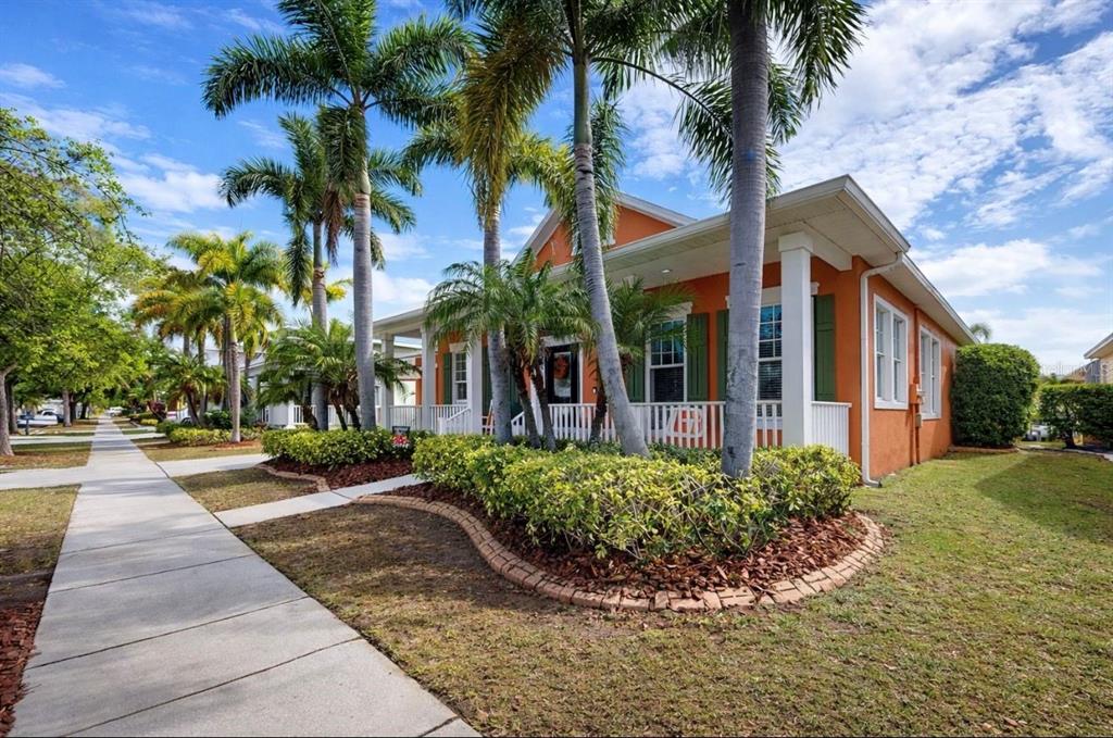 A single-story orange house with a two-car garage, front porch, and palm trees — 5715 SEA TROUT PLACE, APOLLO BEACH, FL