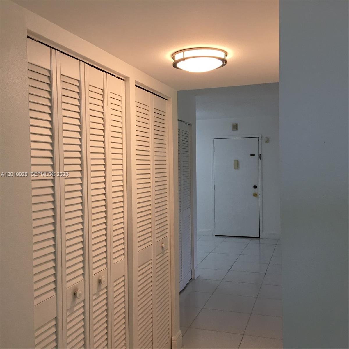 A hallway features white louvered closet doors, tiled flooring, and a flush-mount ceiling light — 7995 SW 86th St # 322, Miami FL 33143, MIAMI, FL