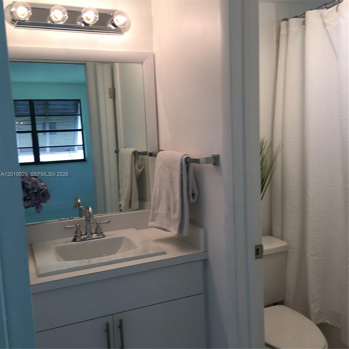 A bathroom features a white vanity with a sink, a mirror, and a shower curtain — 7995 SW 86th St # 322, Miami FL 33143, MIAMI, FL