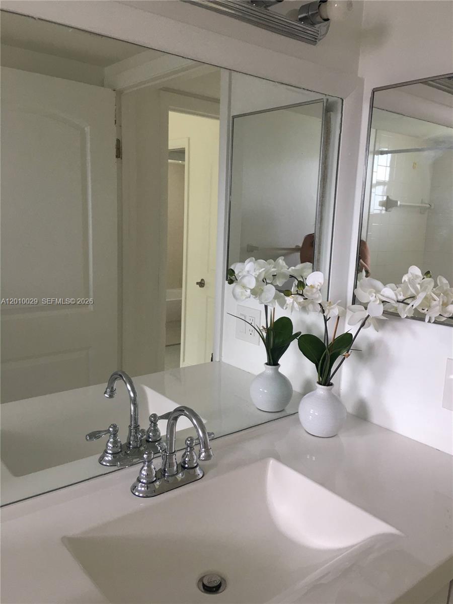 A bathroom features a white vanity, a chrome faucet, and two potted white orchid arrangements — 7995 SW 86th St # 322, Miami FL 33143, MIAMI, FL