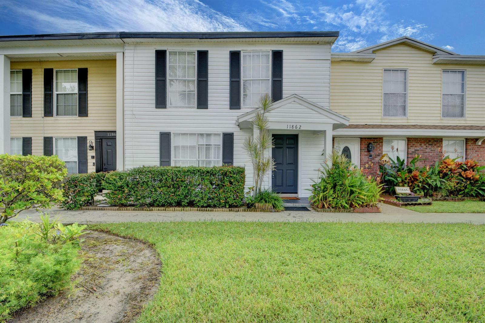 A two-story townhouse exterior with white siding, black shutters, and a small front porch — 11862 E Brier Patch Ct Court, Wellington FL 33414, WELLINGTON, FL
