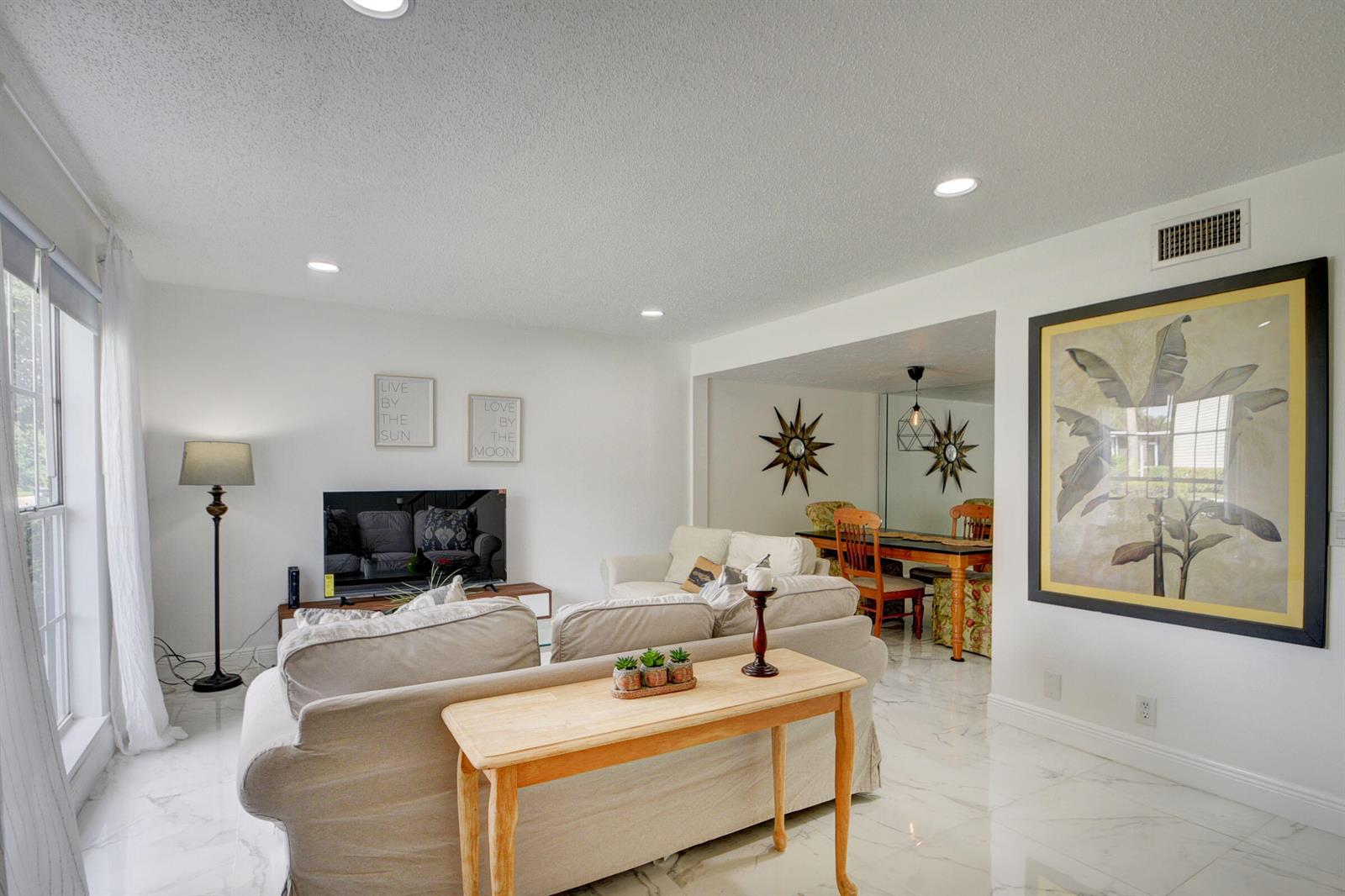A living room with white marble floors, a beige sofa, and a dining area beyond — 11862 E Brier Patch Ct Court, Wellington FL 33414, WELLINGTON, FL