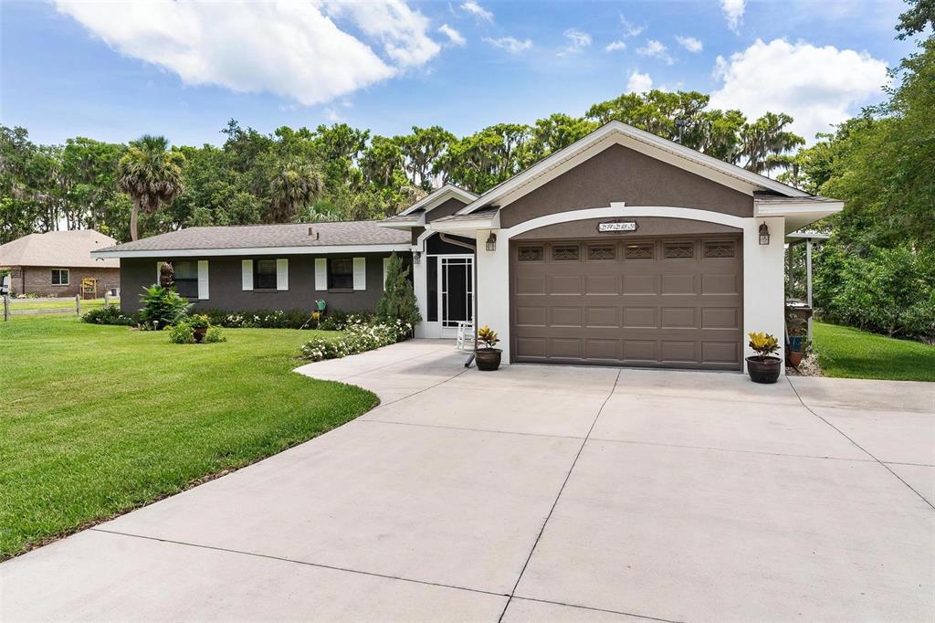 A single-story house with a brown exterior, white trim, and a two-car garage — 29205 S CORLEY ISLAND ROAD, LEESBURG, FL