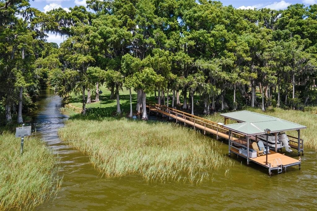 An aerial view shows a wooden dock with a boat lift extending into a lake — 29205 S CORLEY ISLAND ROAD, LEESBURG, FL