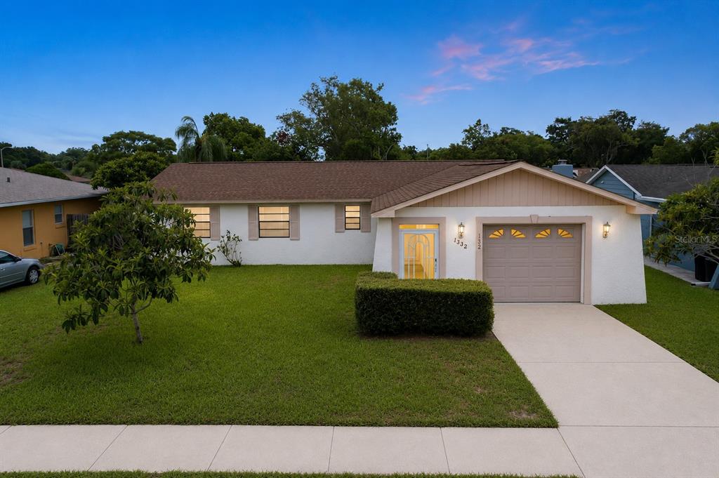 A single-story house with a white stucco exterior, brown roof, and an attached garage — 12132 SHADOW RIDGE BOULEVARD, HUDSON, FL