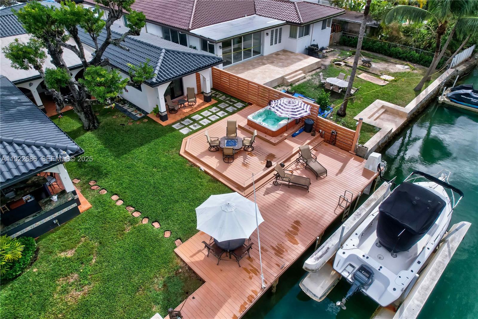 An aerial view of a waterfront backyard featuring a wooden deck, hot tub, and boat — 7724 Hawthorne Ave, Miami Beach FL 33141, MIAMI BEACH, FL