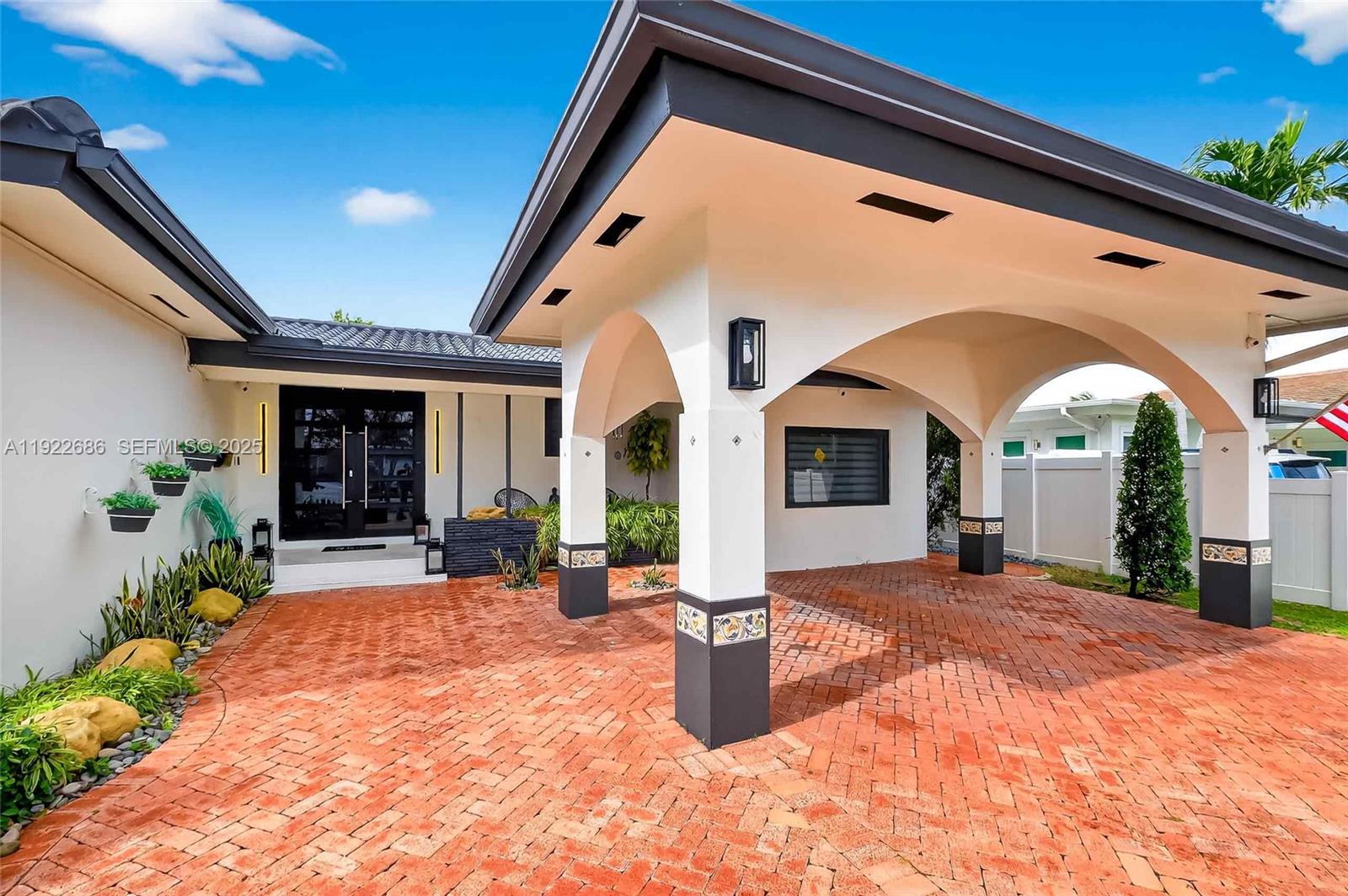 A house exterior features a covered brick driveway with arched supports and a modern entrance — 7724 Hawthorne Ave, Miami Beach FL 33141, MIAMI BEACH, FL